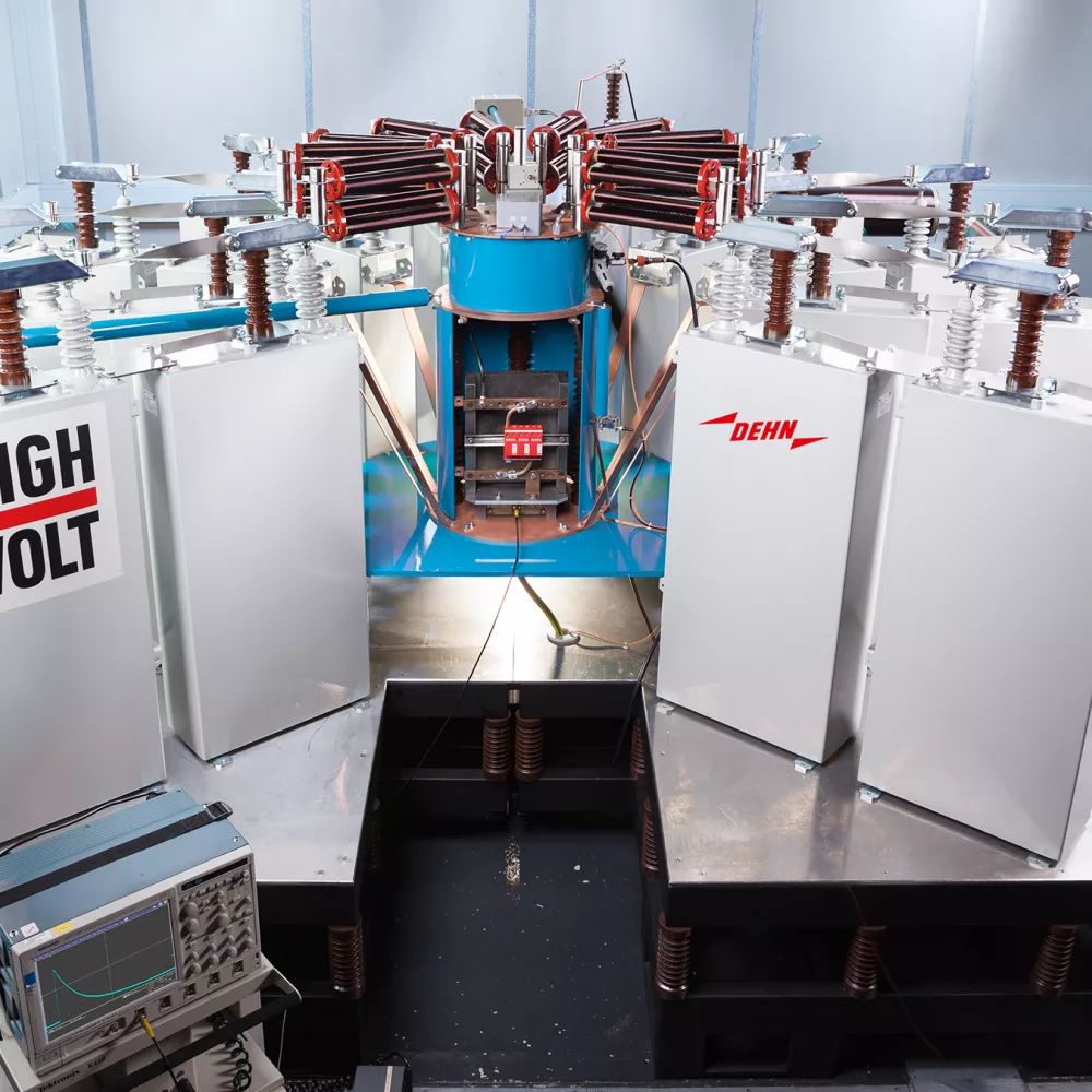 High-voltage testing apparatus with multiple insulated compartments and a central, blue-and-red component, situated in a laboratory setting.