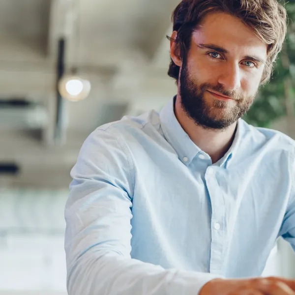 Mann im hellblauen Hemd am Laptop im modernen Büro mit Pflanzen – digitales Arbeiten.