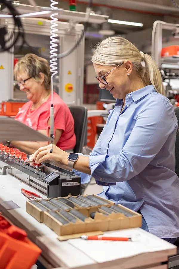 Zwei Personen arbeiten an Maschinen in einer Werkstatt.