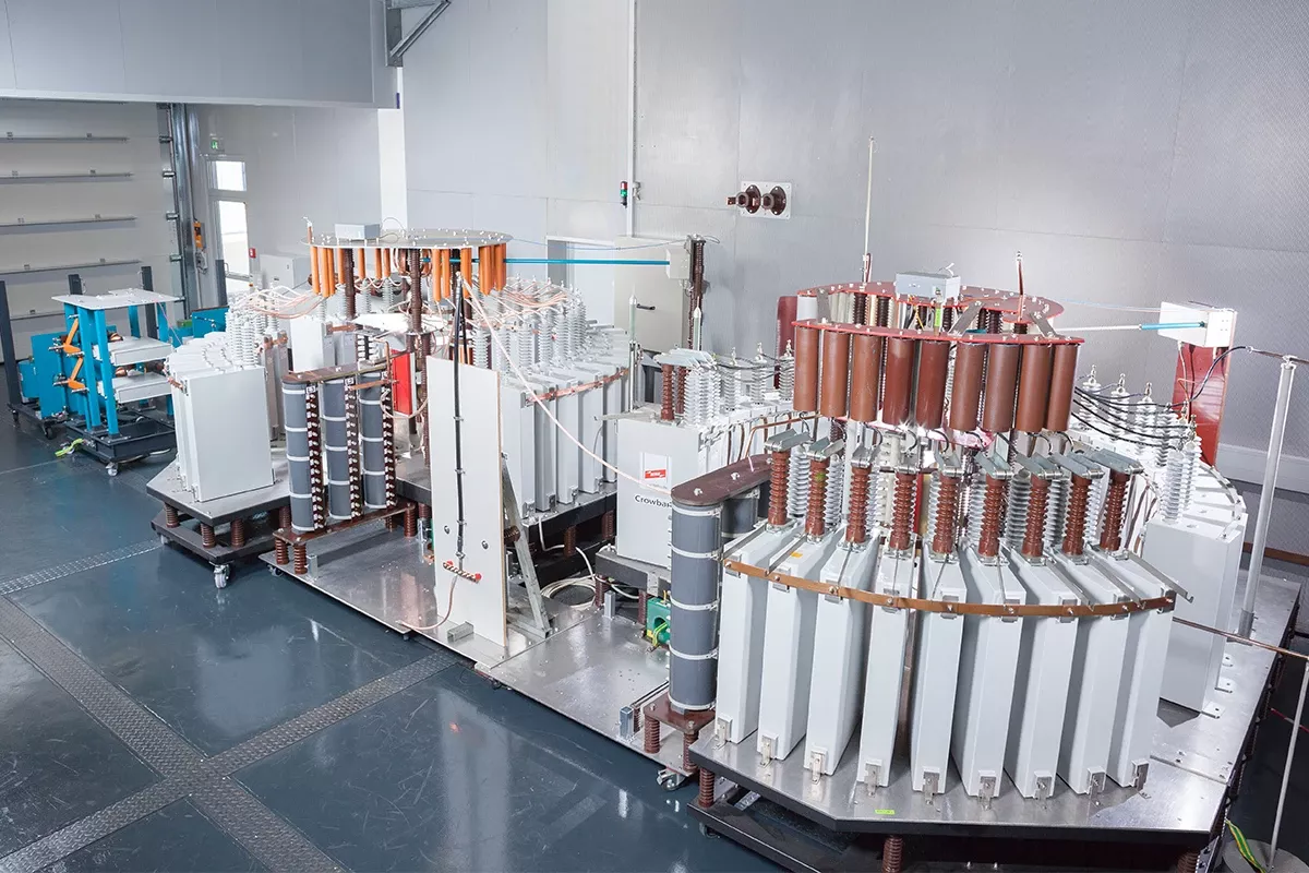 High-voltage lightning impulse current generator in a test laboratory with large transformers and insulators.